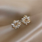 Gros plan sur une boucle d'oreille puce florale, mettant en valeur les détails des pétales opalescents et la structure dorée entrelacée, Maison Mercier.