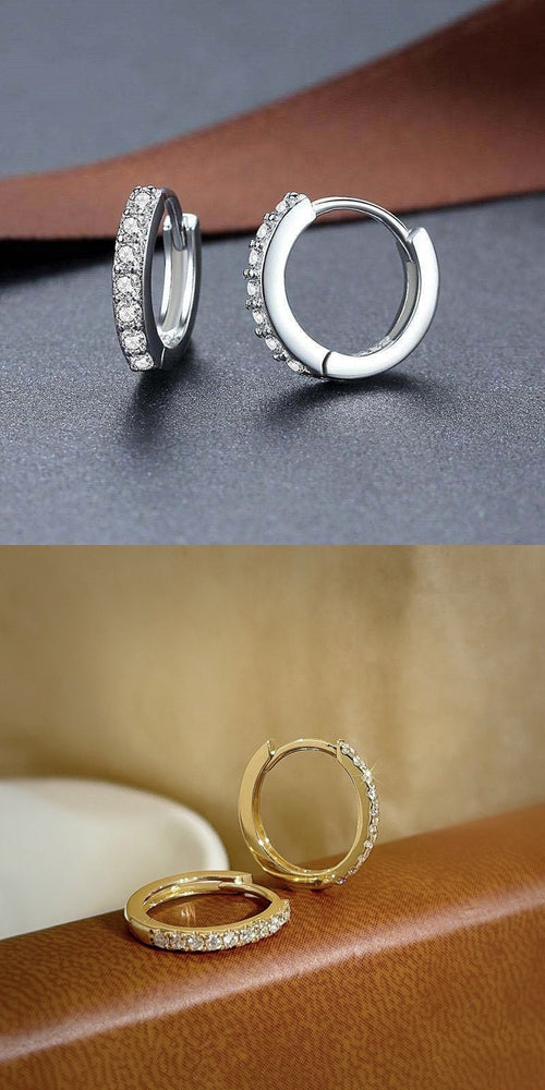 Détail d'une paire de créoles mini huggie en Argent 925 plaqué or, serties de zircons scintillants, posées sur un cuir patiné, Maison Mercier.
