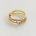 Perspective oblique d'une bague double rangée en plaqué or 18K, sertie de zircons scintillants, sur une surface marbrée, Maison Mercier.