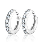 Détail d'une paire de créoles mini huggie en Argent 925 plaqué or, serties de zircons scintillants, posées sur un cuir patiné, Maison Mercier.