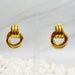 Paire de boucles d'oreilles anneaux entrelacés dorés en acier inoxydable présentées sur un support transparent, Maison Mercier.