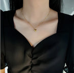 Vue rapprochée d'un collier pendentif cœur 'Love' doré porté par une femme, mettant en valeur la délicatesse du bijou et de la chaîne, Maison Mercier.