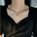 Vue rapprochée d'un collier pendentif cœur 'Love' doré porté par une femme, mettant en valeur la délicatesse du bijou et de la chaîne, Maison Mercier.