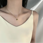 Détail d'un collier pendentif cœur 'Love' en acier inoxydable doré poli, posé sur un tissu élégant, Maison Mercier.