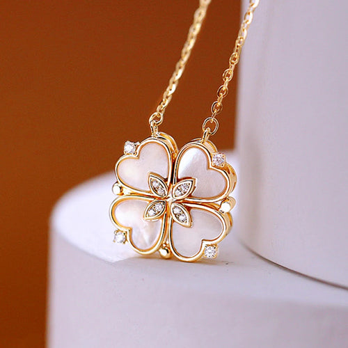 Collier pendentif transformable cœurs trèfle en acier doré et zirconia, présenté ouvert en ligne de cœurs et fermé en trèfle, sur fond bleu profond, Maison Mercier.
