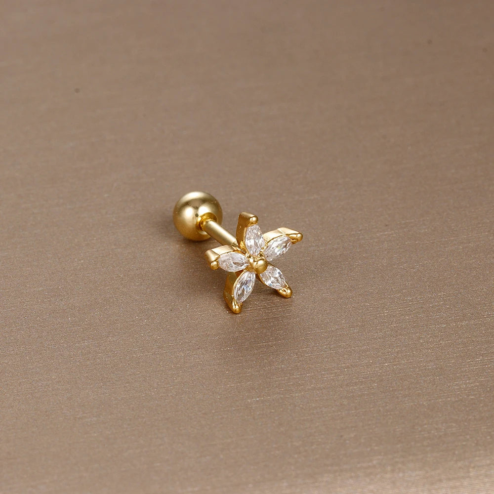 Détail d'un piercing d'oreille croix latine ornée de zircons, en acier chirurgical doré, Maison Mercier.