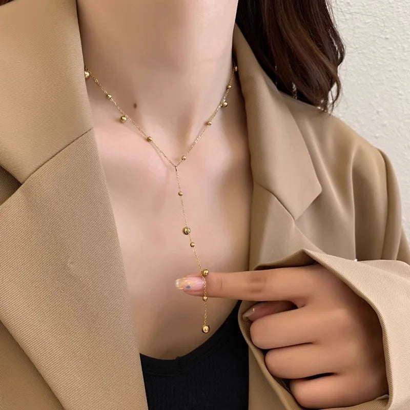 Vue d'ensemble du collier Lariat Y doré, montrant la chaîne et les sphères, avec son fermoir réglable.