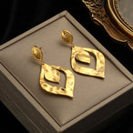 Détail d'une paire de boucles d'oreilles dorées en éventail avec des motifs géométriques émaillés rouges, Maison Mercier.