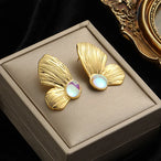 Rendu artistique des boucles d'oreilles sculpturales dorées, soulignant leur aspect liquide et moderne, Maison Mercier.