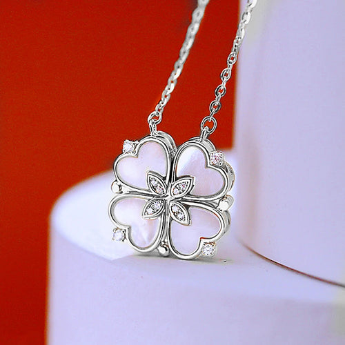 Collier pendentif transformable cœurs trèfle en acier doré et zirconia, présenté ouvert en ligne de cœurs et fermé en trèfle, sur fond bleu profond, Maison Mercier.