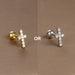 Gros plan artistique d'un piercing d'oreille fleur à cinq pétales en zircons, en acier chirurgical doré, sur fond bronze, Maison Mercier.