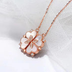 Collier pendentif transformable cœurs trèfle en acier doré et zirconia, présenté ouvert en ligne de cœurs et fermé en trèfle, sur fond bleu profond, Maison Mercier.