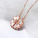 Collier pendentif transformable cœurs trèfle en acier doré et zirconia, présenté ouvert en ligne de cœurs et fermé en trèfle, sur fond bleu profond, Maison Mercier.