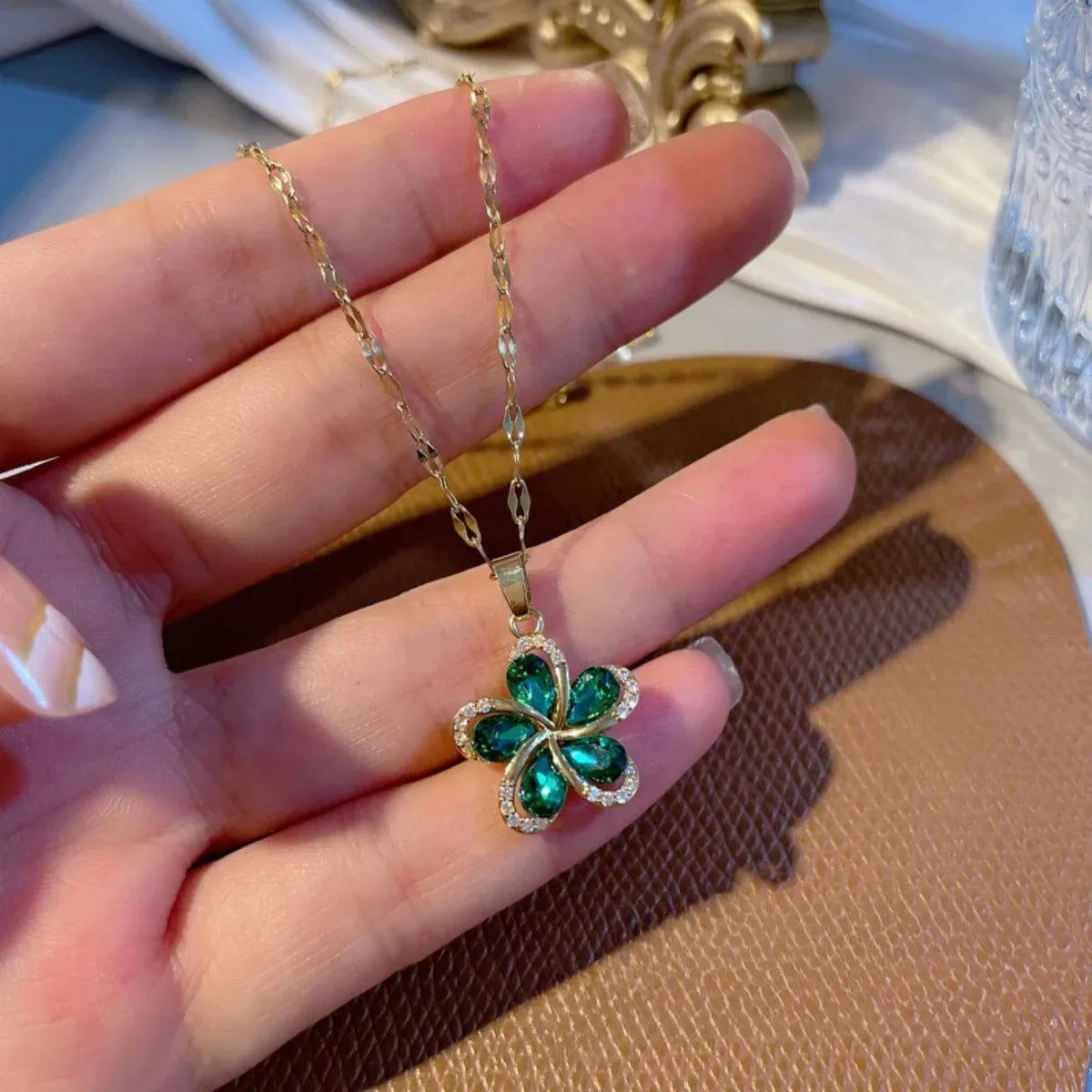 Détail d'un Collier Pendentif Floral vert en acier doré, porté avec élégance, mettant en valeur la brillance des zircons.