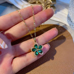 Détail d'un Collier Pendentif Floral vert en acier doré, porté avec élégance, mettant en valeur la brillance des zircons.