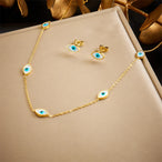 Gros plan sur une parure collier et puces d'oreilles mandala ajouré en acier doré et turquoise, Maison Mercier.