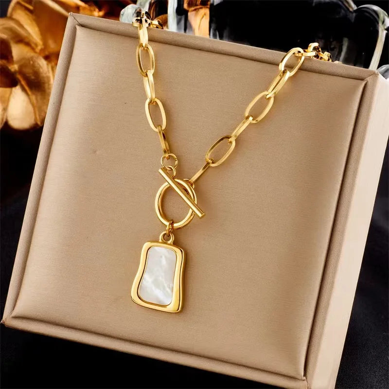 Détail d'un collier chaîne à maillons ovales dorés avec fermoir T-bar et pendentif nacre rectangulaire, Maison Mercier.