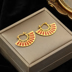 Détail d'une paire de boucles d'oreilles dorées en forme de soleil stylisé avec des rayons ciselés, Maison Mercier.