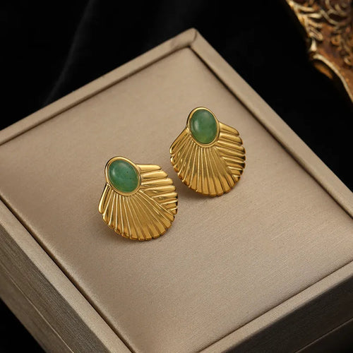 Gros plan d'une paire de boucles d'oreilles créoles dorées à la texture fondue et irrégulière, posées sur un écrin beige, Maison Mercier.
