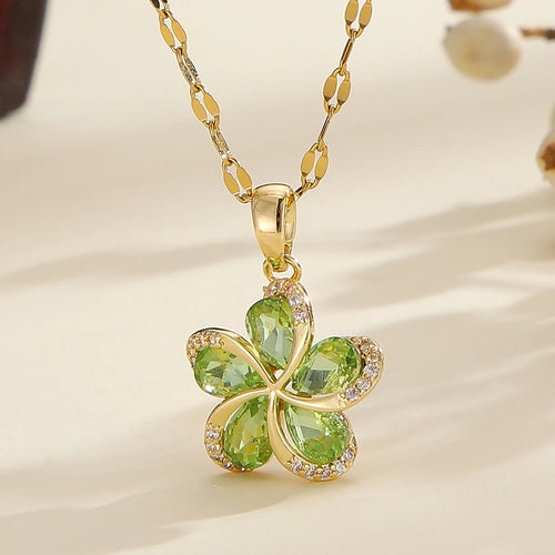 Vue d'ensemble de trois Colliers Pendentifs Floraux Maison Mercier, ornés de zircons blancs, verts et rouges, en acier doré.