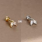 Détail d'un piercing d'oreille motif carré orné de zircons, en acier chirurgical doré, Maison Mercier.