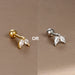 Détail d'un piercing d'oreille motif carré orné de zircons, en acier chirurgical doré, Maison Mercier.