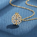 Collier pendentif transformable cœurs trèfle en acier doré et zirconia, présenté ouvert en ligne de cœurs et fermé en trèfle, sur fond bleu profond, Maison Mercier.