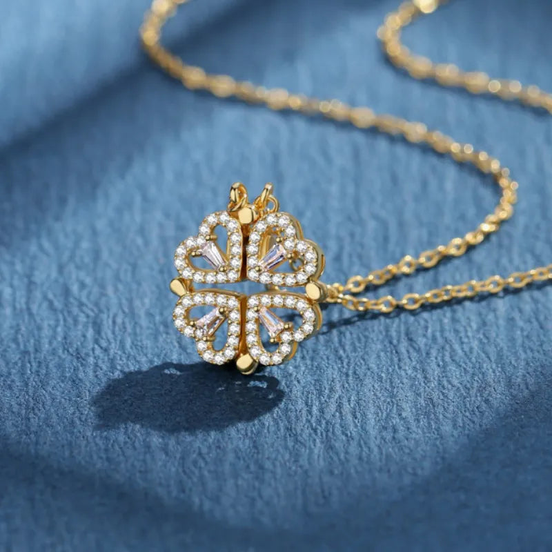 Collier pendentif transformable cœurs trèfle en acier doré et zirconia, présenté ouvert en ligne de cœurs et fermé en trèfle, sur fond bleu profond, Maison Mercier.