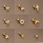 Détail d'un piercing d'oreille fleur à cinq pétales en zircons, en acier chirurgical doré, Maison Mercier.