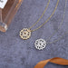 Collier pendentif transformable cœurs trèfle en acier doré et zirconia, présenté ouvert en ligne de cœurs et fermé en trèfle, sur fond bleu profond, Maison Mercier.