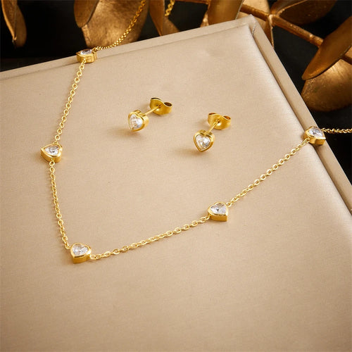 Détail d'une parure collier et puces d'oreilles petits cœurs en acier doré, Maison Mercier.