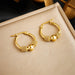 Paire de boucles d'oreilles doubles anneaux en acier inoxydable doré, avec dimensions (1.5cm) et poids (5g), Maison Mercier.