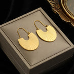 Détail d'une paire de boucles d'oreilles dorées en forme de feuille stylisée avec une pierre opale, Maison Mercier.