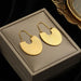 Détail d'une paire de boucles d'oreilles dorées asymétriques avec un cœur et une étoile sertis de zircons, Maison Mercier.
