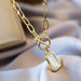 Texture et brillance des maillons ovales dorés du collier, témoignant d'un artisanat précis, Maison Mercier.