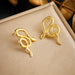 Paire de boucles d'oreilles puces en forme de cœur stylisé en acier inoxydable doré, avec dimensions (1.8cm x 1.5cm) et poids (4g), Maison Mercier.