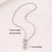 Collier Grains de Café en acier inoxydable doré, fermoir toggle, posé sur un tissu blanc et une pierre texturée, Maison Mercier.