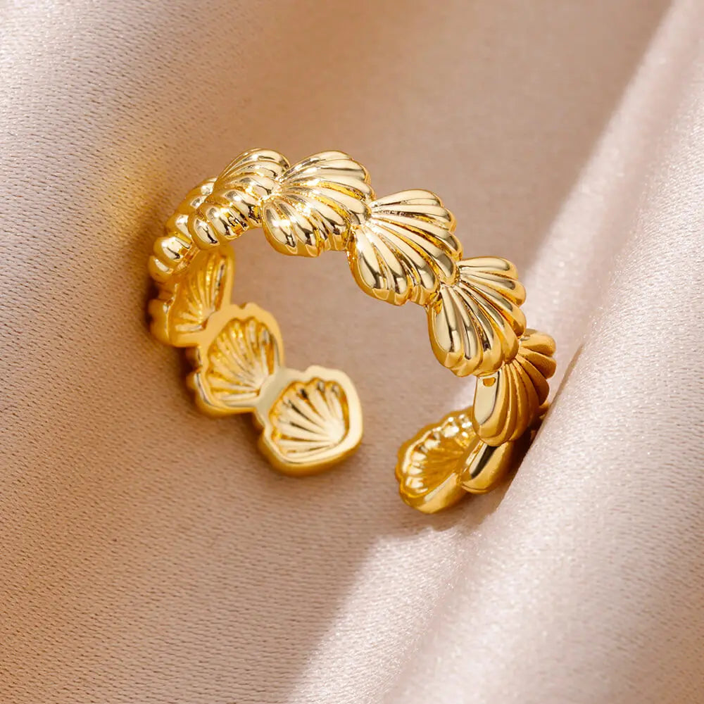 Détail d'une bague ajustable dorée en acier inoxydable, ornée d'un motif délicat de coquillages, Maison Mercier.