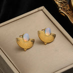 Vue rapprochée du fermoir et de la finition polie des boucles d'oreilles éventail dorées, Maison Mercier.