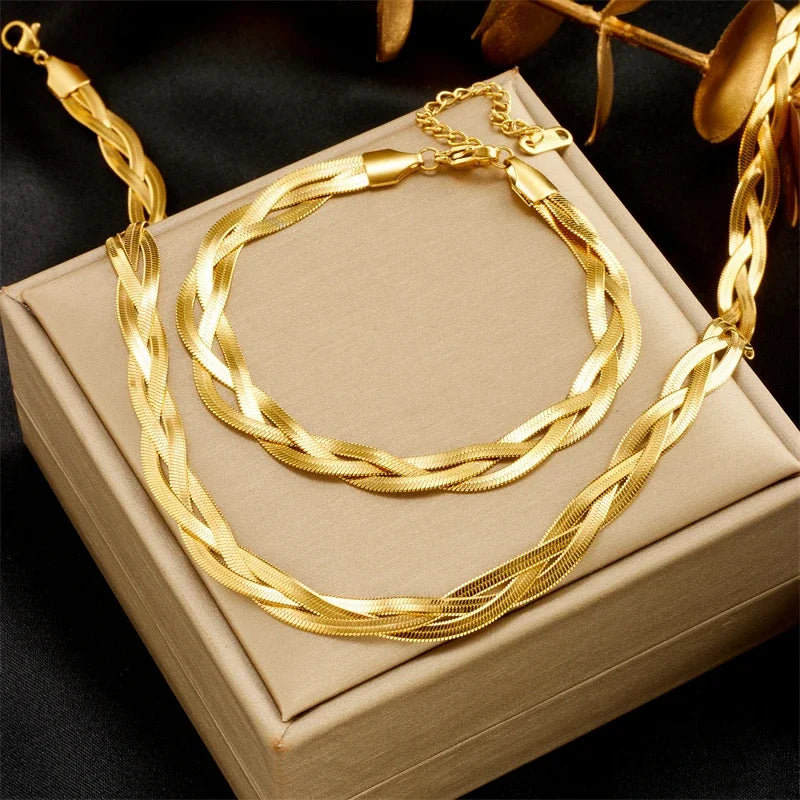 Parure collier et bracelet tressés en maille serpent, finition dorée éclatante, présentée sur un écrin, Maison Mercier.