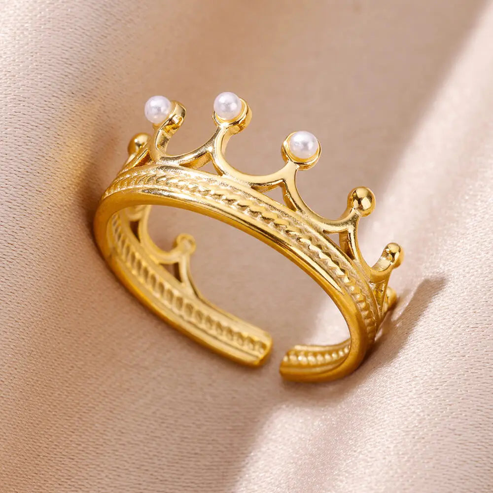 Vue rapprochée d'une bague ajustable dorée en acier inoxydable, présentant un élégant motif de couronne rehaussé de perles fines, Maison Mercier.