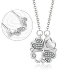 Collier pendentif transformable cœurs trèfle en acier doré et zirconia, présenté ouvert en ligne de cœurs et fermé en trèfle, sur fond bleu profond, Maison Mercier.