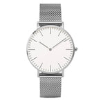 Montre féminine Maison Mercier, cadran noir épuré, bracelet maille milanaise finition or rose, portée au poignet avec un bracelet délicat à perles dorées.