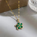 Collier Pendentif Floral vert en acier doré, posé délicatement sur une surface claire, illustrant la finesse de son design.