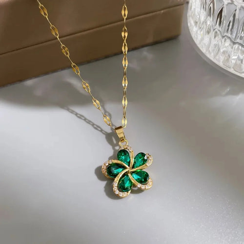 Vue d'ensemble de trois Colliers Pendentifs Floraux Maison Mercier, ornés de zircons blancs, verts et rouges, en acier doré.