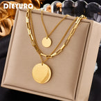 Détail d'un collier superposé doré avec maillons rectangulaires et disques polis, présenté sur un écrin beige, Maison Mercier.