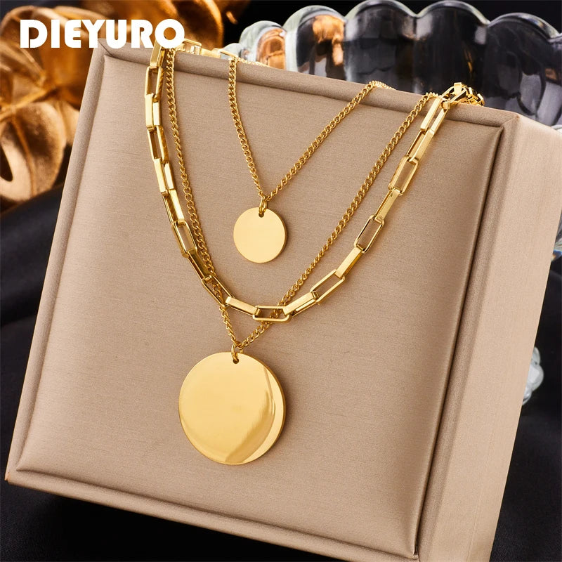 Détail d'un collier superposé doré avec maillons rectangulaires et disques polis, présenté sur un écrin beige, Maison Mercier.