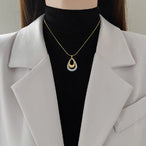 Pendentif bicolore en acier inoxydable, capturant la lumière avec ses finitions or et argent.