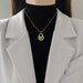 Pendentif bicolore en acier inoxydable, capturant la lumière avec ses finitions or et argent.
