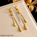 Détail des boucles d'oreilles pendantes Goutte d'Eau en acier doré, avec leurs dimensions précises de 7.5 cm (2.95 inch) et un poids de 14g (0.5oz), Maison Mercier.